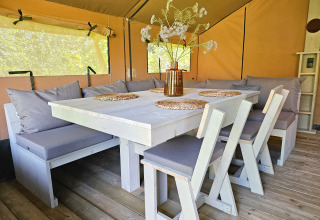 Gemütlicher Essbereich in einem Safarizelt bei Minicamping Sint Jan – Safaritenten Zeeland, mit Kissen.