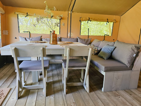 Interieur van luxe safaritent bij Minicamping Sint Jan met gezellige eethoek en grote ramen in Zeeland.