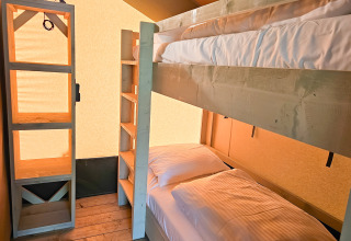 Moderne glampingaccommodatie met stapelbedden en houten meubels bij Minicamping Sint Jan - Safaritenten Zeeland.