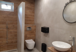 Salle de bain moderne au Minicamping Sint Jan - Safaritenten Zeeland avec douche, toilettes et vasque.
