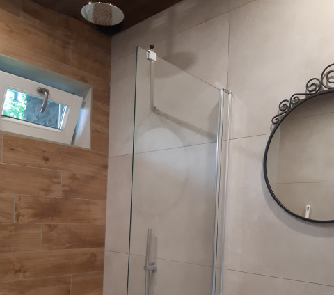 Douche de salle de bain moderne, porte en verre, miroir rond et petite fenêtre au Minicamping Sint Jan, Zeeland.