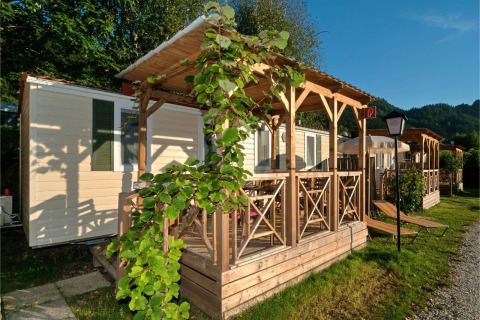 Outdoor view of Wellnesscamping & Landhuis Parth - Stacaravans Austria with wooden porch and lush greenery.