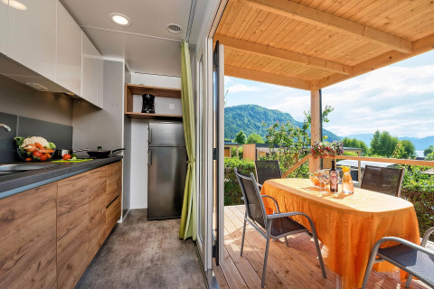 Moderne glamping accommodatie met keuken en terras, eettafel en uitzicht op bergen bij Wellnesscamping & Landhuis Parth.