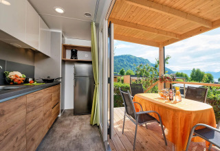 Moderne glamping accommodatie met keuken en terras, eettafel en uitzicht op bergen bij Wellnesscamping & Landhuis Parth.