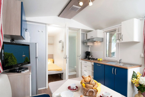 Alojamiento glamping moderno con cocina, comedor, dormitorio y televisor en Wellnesscamping & Landhuis Parth.