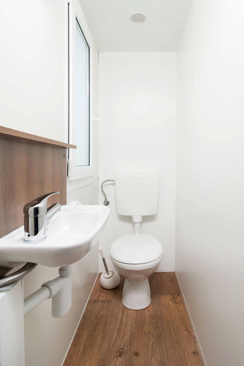 Modern compact bathroom at Wellnesscamping & Landhuis Parth with toilet, sink, and wooden flooring.