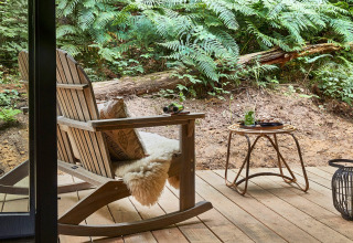 Terraza de madera con mecedora y mesa en el bosque de Buitenplaats Beekhuizen - Forest cabins Veluwe.