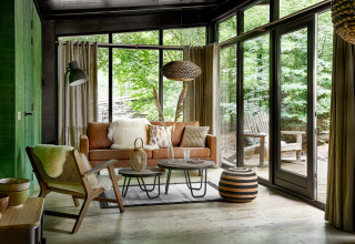 Modern glamping accommodation in the forest at Buitenplaats Beekhuizen – cozy living room with large windows.