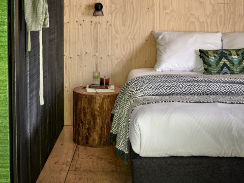 Alojamiento glamping acogedor con paredes de madera, cama y mesa de tronco en Buitenplaats Beekhuizen, Veluwe.