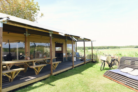 Glamping-accommodatie Duynpark Het Zwanenwater - Woodlodges Noord-Holland met fiets en bank buiten.