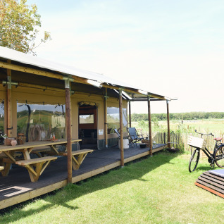 Glamping-Unterkunft Duynpark Het Zwanenwater - Woodlodges Noord-Holland mit Picknicktischen und Fahrrad.