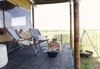 Glampingophold ved Duynpark Het Zwanenwater Woodlodges i Nord-Holland med veranda, stole og bålplads.