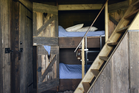 Gemütlicher Holzlodge-Innenraum mit Etagenbetten und karierten Decken im Duynpark Het Zwanenwater.
