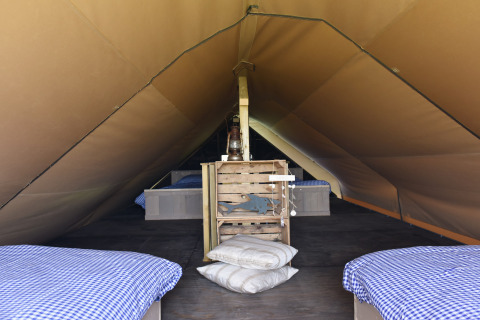 Indretning af en rummelig glamping-teltlodge med senge og plaid på Duynpark Het Zwanenwater i Nordholland.