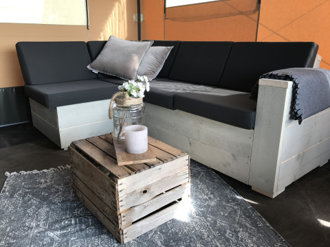 Sfeervolle lounge van glamping Woodlodges Duynpark Het Zwanenwater, Noord-Holland met rustiek meubilair.