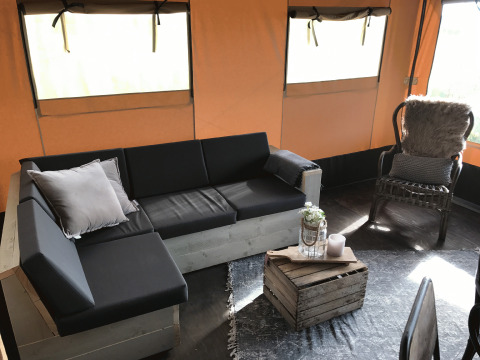 Glamping-accommodatie bij Duynpark Het Zwanenwater Woodlodges in Noord-Holland met zithoek en houten kisttafel.