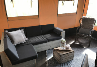Hébergement glamping au Duynpark Het Zwanenwater Woodlodges avec un canapé et une table caisse en bois aux Pays-Bas.