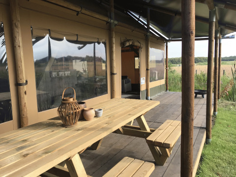 Terrasse mit Picknicktisch bei Duynpark Het Zwanenwater - Woodlodges Noord-Holland, Blick auf Wiesen.