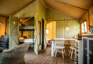 Indretning af glamping-indkvartering i Erfgoed Bossem Lodgetenten Twente med rustikke træmøbler.
