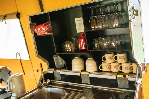 Coin cuisine d’une tente lodge Erfgoed Bossem à Twente avec tasses, verres, torchons et évier.