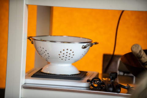 Witte metalen vergiet met handvatten op een plank bij Erfgoed Bossem - Lodgetenten Twente glamping.