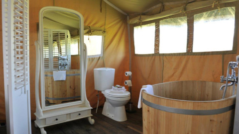 Hébergement glamping Erfgoed Bossem Lodgetenten Twente avec baignoire en bois et grand miroir.
