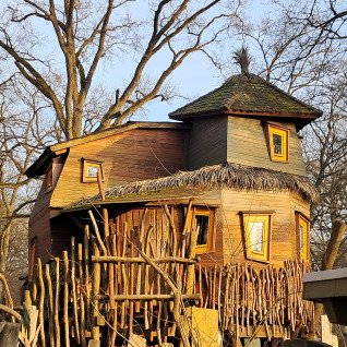 Einzigartige Baumhaus-Unterkunft zum Glamping im Dierentuin Schwerin mit rustikaler Holzkonstruktion.