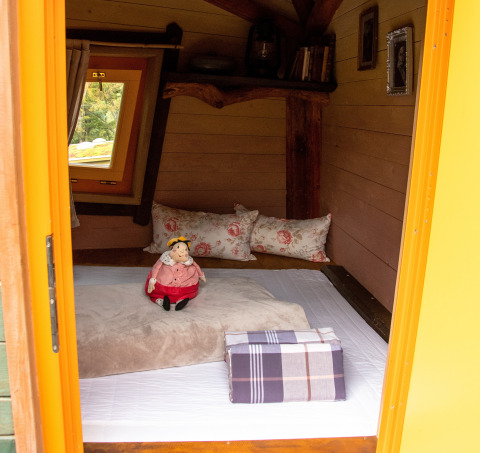 Indvendigt billede af Boomhut-glamping ved Dierentuin Schwerin med bløde puder, dukke og vindue.