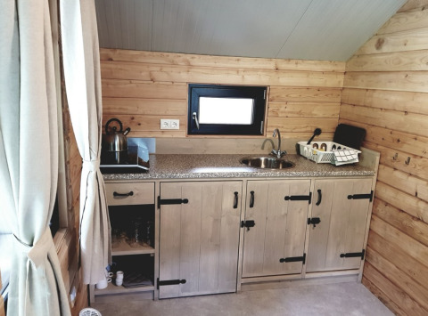 Acogedora cocina de glamping en Camping Alf - Chalets Renania-Palatinado, con paredes de madera y comodidades modernas.