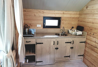 Et hyggeligt glampingkøkken i Camping Alf - Chalets Rijnland-Palts med trævægge og moderne faciliteter.