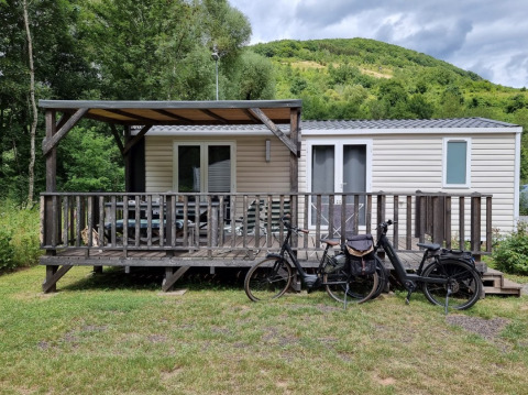 Chalet glamping moderne au Camping Alf - Chalets Rijnland-Palts, terrasse en bois, vélos, et nature environnante.