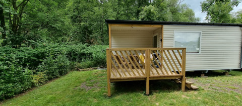 Veranda in legno e chalet glamping al Camping Alf - Chalets Rijnland-Palts circondato dal verde.