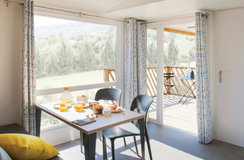 Helles Chalet-Interieur mit Frühstückstisch und Blick zur Terrasse im Camping Alf - Chalets Rheinland-Pfalz.