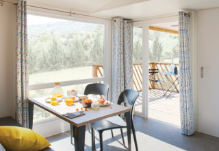 Lichte eethoek met ontbijt en uitzicht op het terras bij Camping Alf - Chalets Rijnland-Palts.