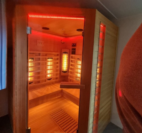Moderne infraroodsauna met houten banken en rode LED-verlichting op Camping Alf - Chalets Rijnland-Palts.