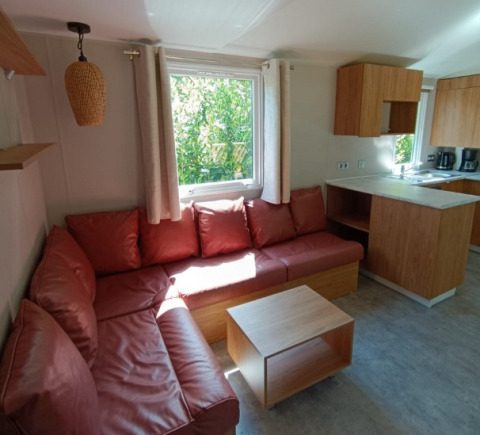 Moderne glamping accommodatie met rode hoekbank bij Camping Alf - Chalets Rijnland-Palts, lichte zithoek.