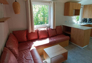 Moderne Glamping-Unterkunft mit roter Eckcouch und Küche in Camping Alf - Chalets Rijnland-Pfalz.