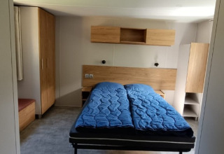 Interieur van een glamping chalet bij Camping Alf - Chalets Rijnland-Palts met tweepersoonsbed en houten meubels.