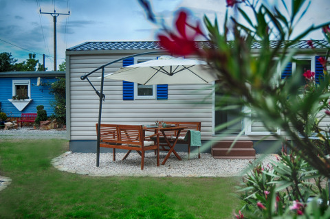 Outdoor dining area with wooden furniture and umbrella in front of luxury glamping cabin at Camping Nahemühle.