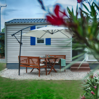 Outdoor dining area with wooden furniture and umbrella in front of luxury glamping cabin at Camping Nahemühle.