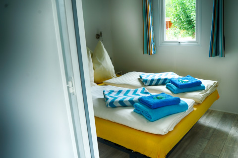 Chambre glamping accueillante au Camping Nahemühle - Luxe stacaravan Rhénanie-Palatinat avec lit prêt et fenêtre.