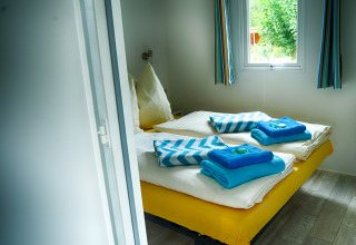 Acogedor dormitorio glamping en Camping Nahemühle - Luxe stacaravan Renania-Palatinado con cama hecha y ventana.