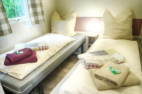 Dos camas individuales con toallas, almohadas y artículos de tocador en glamping de Camping Nahemühle.