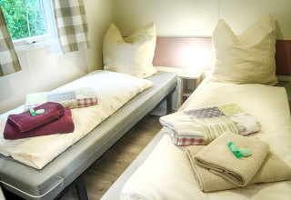 Twee aparte bedden, verse handdoeken en toiletartikelen in glamping stacaravan Camping Nahemühle.