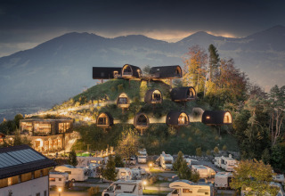Collina con chalet di glamping di lusso e camper di notte ad Alpencamping Nenzing in Voralberg, Austria.