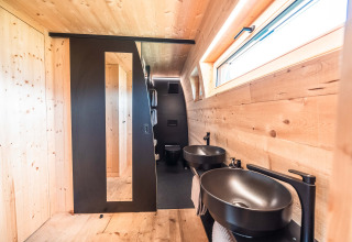 Moderne badkamer met houten afwerking en zwarte details in Alpencamping Nenzing premium chalet te Vorarlberg.