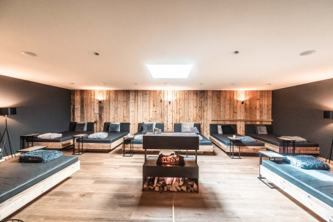 Sala de relajación de lujo con camas modernas, paredes de madera y chimenea en Alpencamping Nenzing, Vorarlberg.