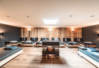 Luxe ontspanningsruimte met moderne bedden, houten wanden en haard in Alpencamping Nenzing, Vorarlberg.