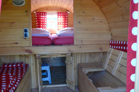Interior de una cabaña glamping de madera con textiles de lunares en Camping Ostseequelle, Wijnvaten Ostzee.