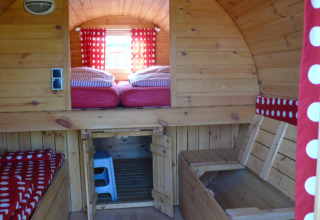 Innenraum eines Holz-Glamourzelts mit roten Bettbezügen bei Camping Ostseequelle - Wijnvaten Ostsee.